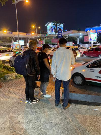 “Cò” taxi (mặc áo trắng) đang ra giá với nhóm khách đi Tây Ninh. Ảnh: THU HỒNG