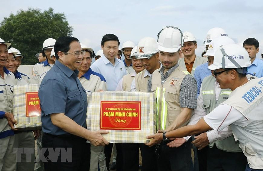 Thủ tướng Phạm Minh Chính tặng quà cho công nhân đang xây dựng dự án tuyến đường Đông-Tây giai đoạn 1. (Ảnh: Dương Giang/TTXVN)