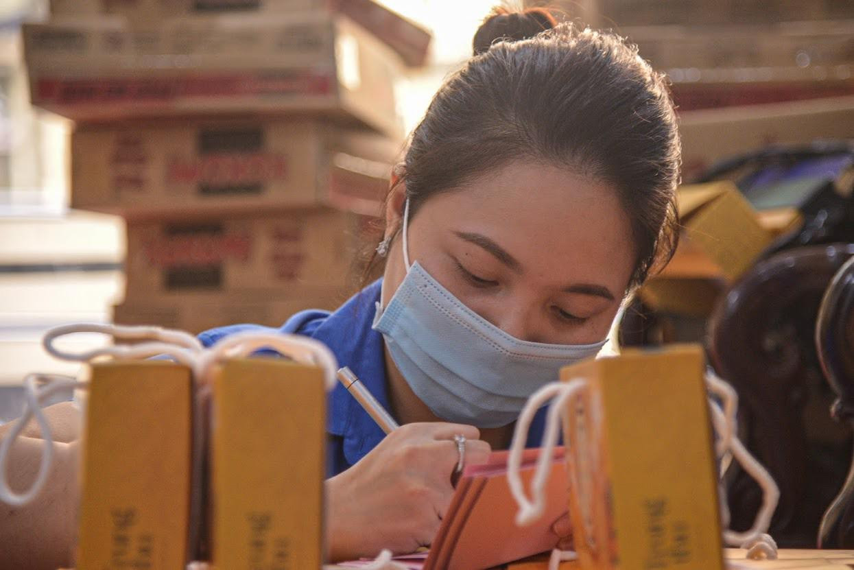 Các anh chị đoàn viên trực tiếp viết những tấm thiệp đính kèm vào từng túi bánh gửi tặng các em