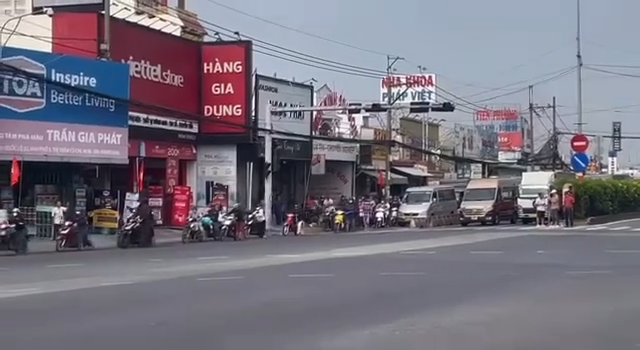 Ô tô đứng yên, trong khi người đi xe máy xếp hàng dài dẫn bộ xe qua giao lộ. Ảnh cắt từ clip.