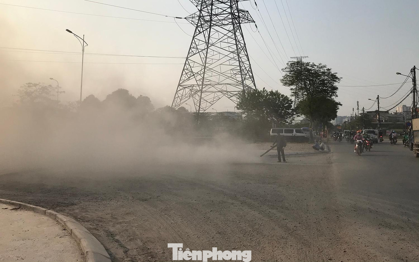Một công nhân dùng máy thổi bề mặt đường đang xây dựng khiến bụi bay mù mịt Một công nhân dùng máy thổi bề mặt đường đang xây dựng khiến bụi bay mù mịt