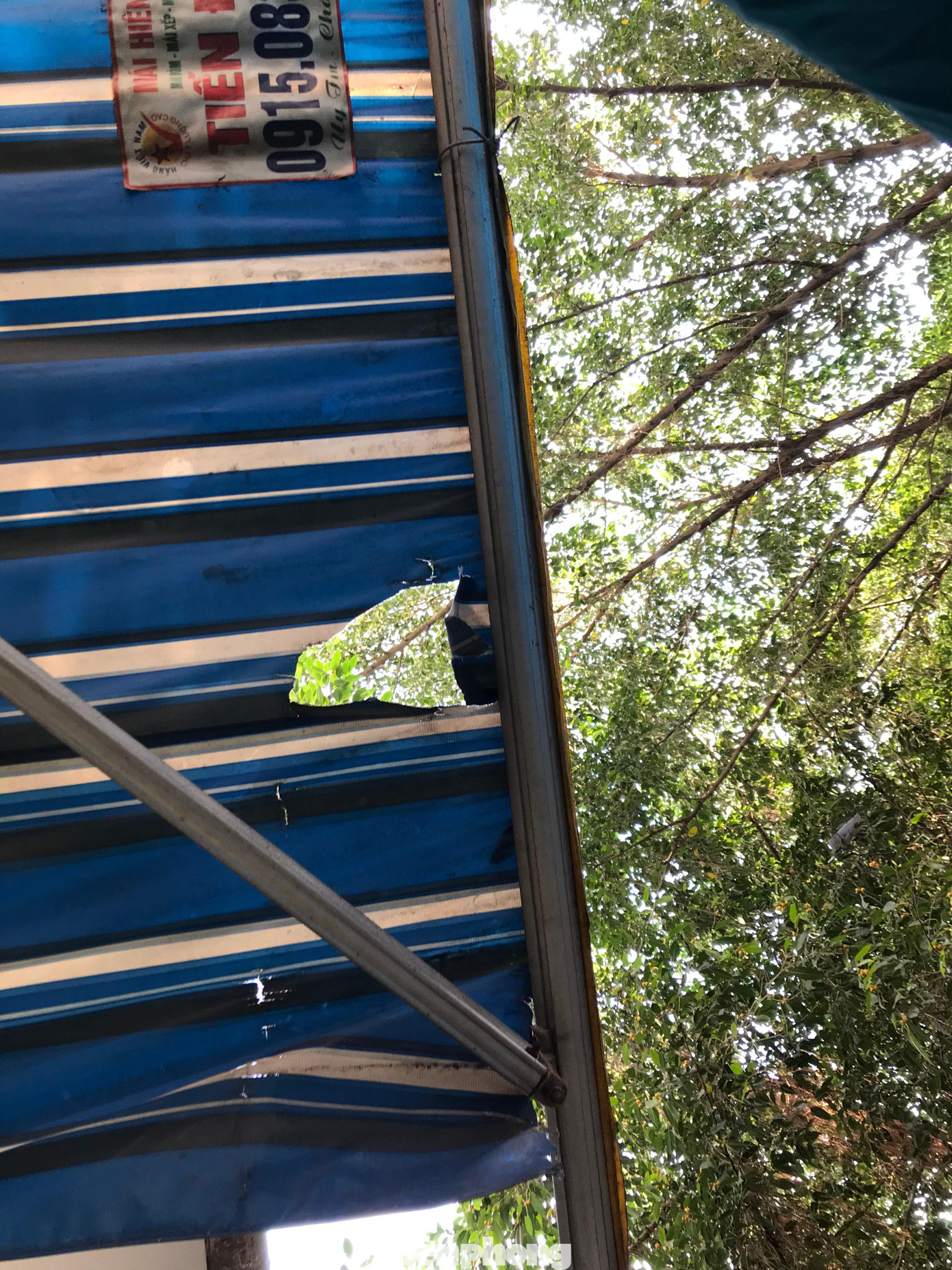 Tấm bạt che bên trên cửa hàng bị rách do bịch rác rơi trúng. Ảnh: Trường Phong