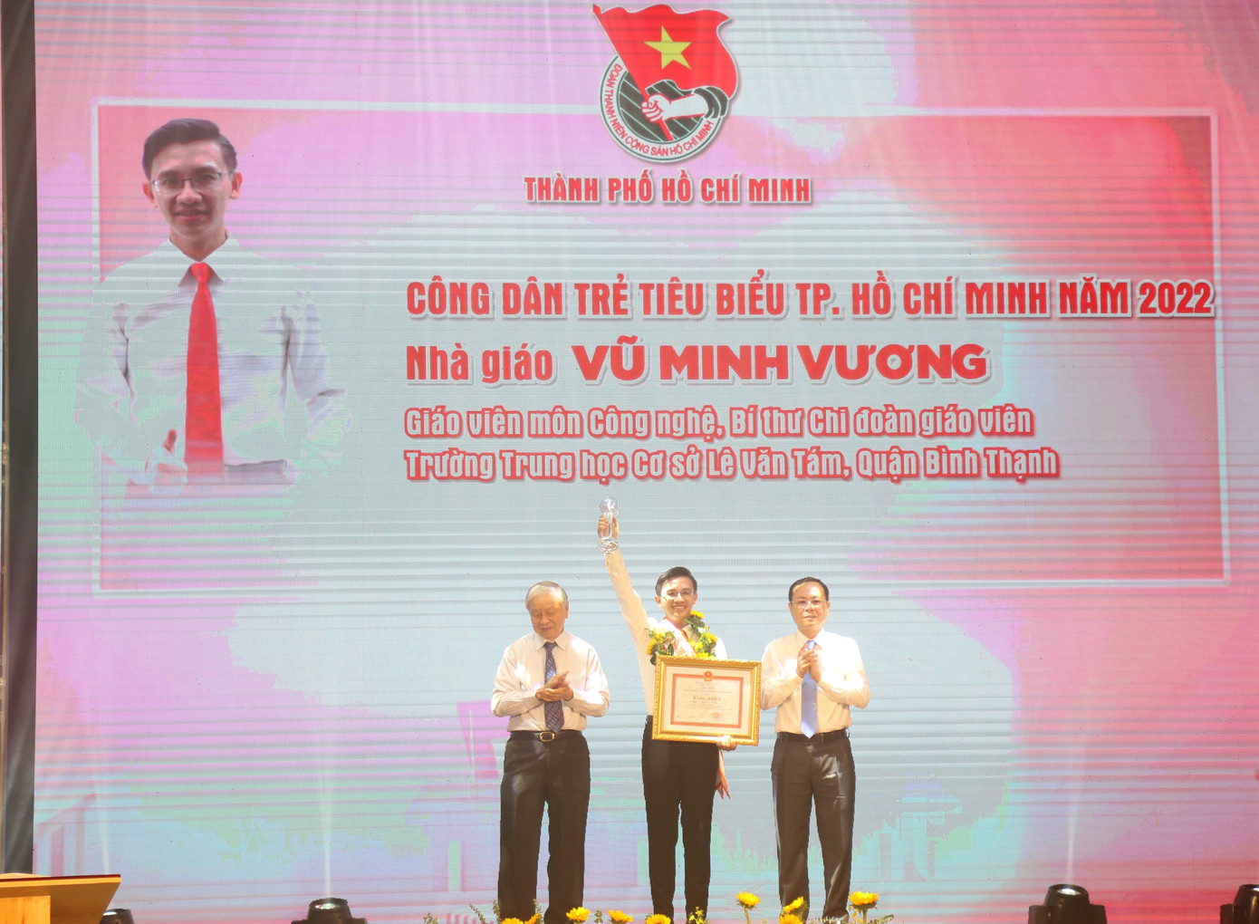 Ông Nguyễn Văn Hiếu, Phó Bí thư Thành ủy TPHCM (bên phải) và ông Phạm Chánh Trực, nguyên Phó Bí thư Thường trực Thành ủy, nguyên Chủ tịch HĐND TPHCM, Chủ nhiệm CLB Truyền thống Thành Đoàn (bên trái) trao hoa và bằng khen tặng nhà giáo Vũ Minh Vương, Giáo viên môn Công nghệ, Bí thư Chi đoàn giáo viên Trường THCS Lê Văn Tám, quận Bình Thạnh.