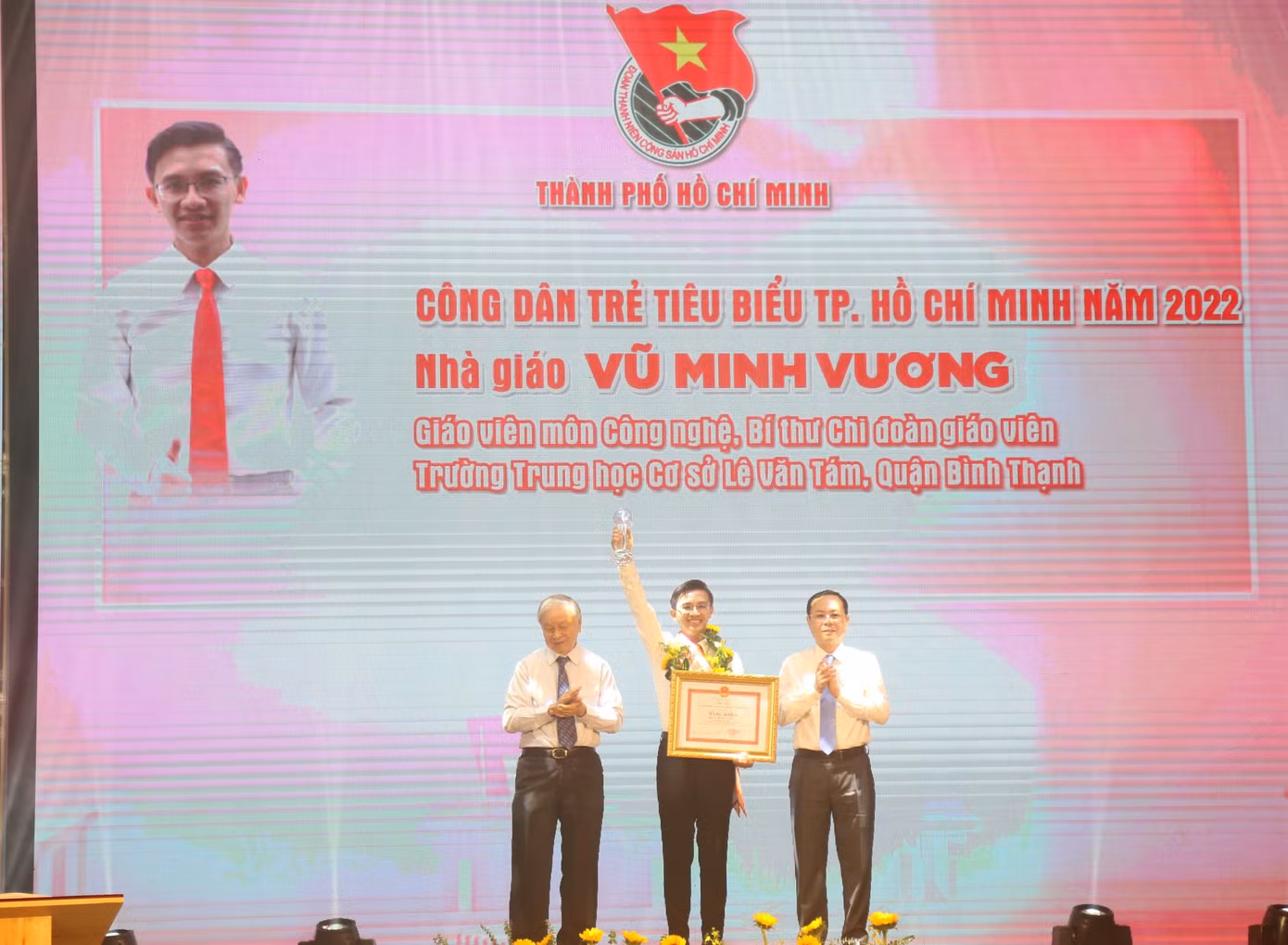 Ông Nguyễn Văn Hiếu, Phó Bí thư Thành ủy TPHCM (bên phải) và ông Phạm Chánh Trực, nguyên Phó Bí thư Thường trực Thành ủy, nguyên Chủ tịch HĐND TPHCM, Chủ nhiệm CLB Truyền thống Thành Đoàn (bên trái) trao hoa và bằng khen tặng nhà giáo Vũ Minh Vương, Giáo viên môn Công nghệ, Bí thư Chi đoàn giáo viên Trường THCS Lê Văn Tám, quận Bình Thạnh.