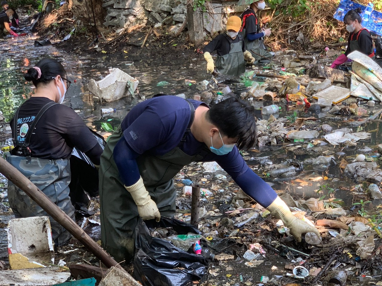 Các bạn trẻ xuống con kênh nước đen để dọn rác.