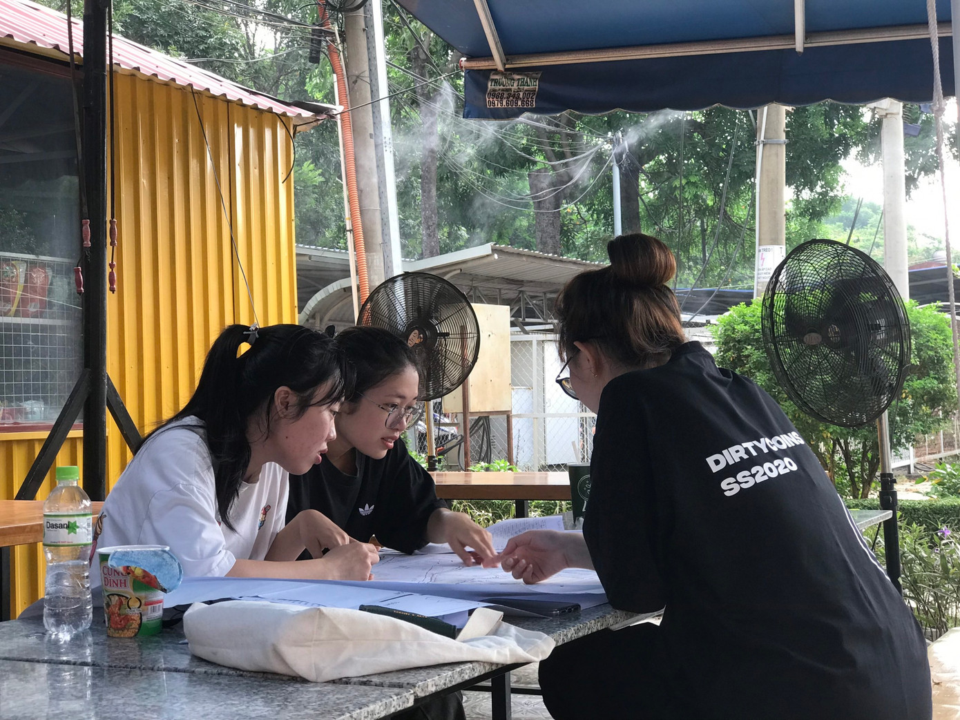 Các bạn sinh viên tránh nắng nóng bằng cách ngồi quán cà phê để lấy hơi mát từ quạt và vòi nước phun sương.