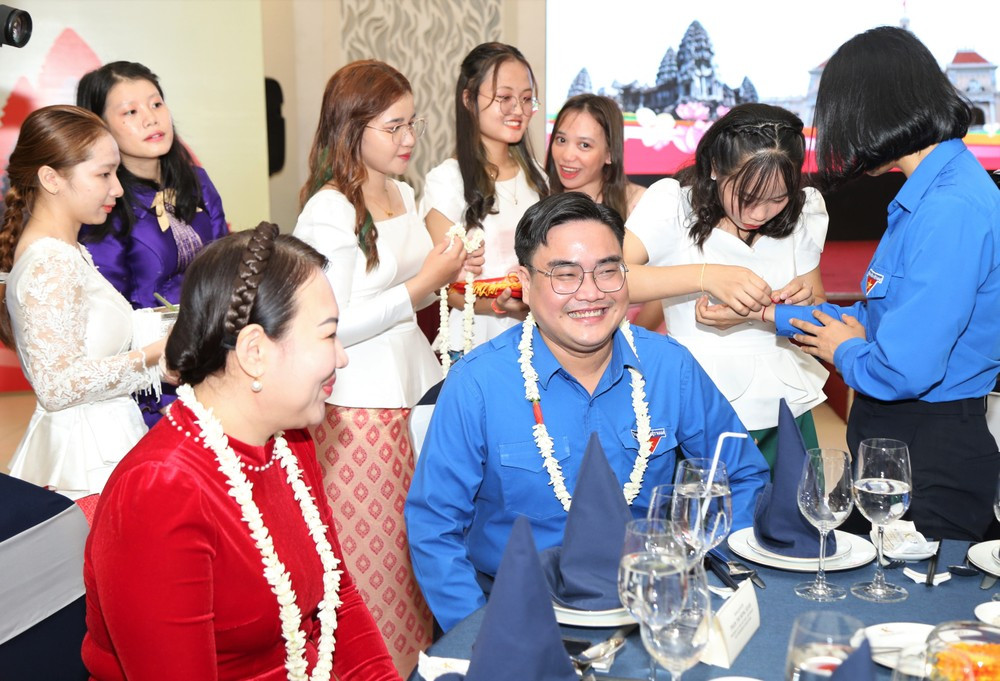 Các bạn sinh viên Lào, Campuchia thực hiện buộc chỉ cổ tay và té nước chúc may mắn đến các đại biểu dự chương trình. (Ảnh: Ngô Tùng)