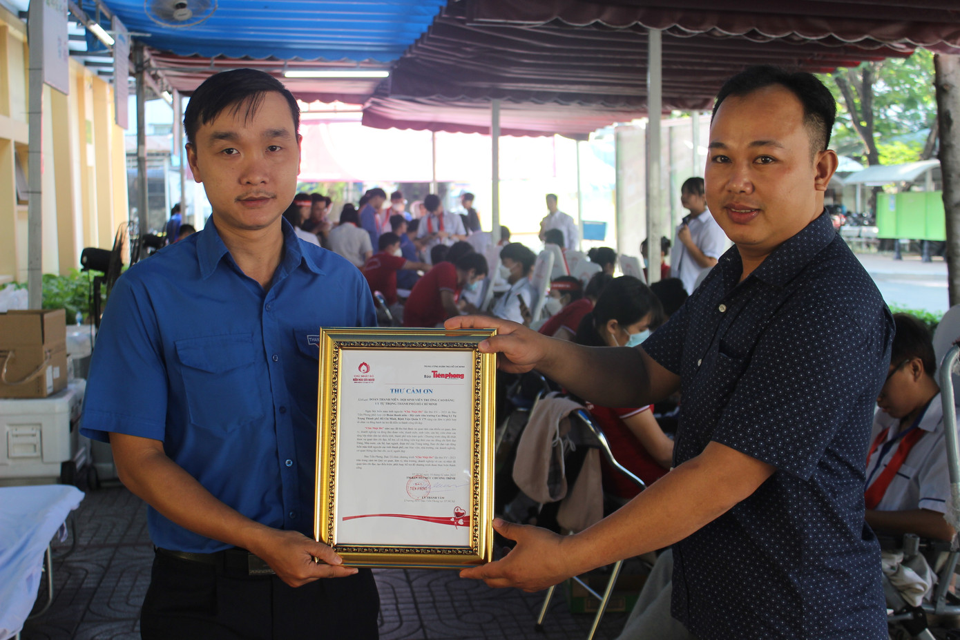 Anh Bùi Đức Phước - Phó bí thư Đoàn trường CĐ Lý Tự Trọng (bên trái) nhận thư cảm ơn của đại diện báo Tiền Phong.