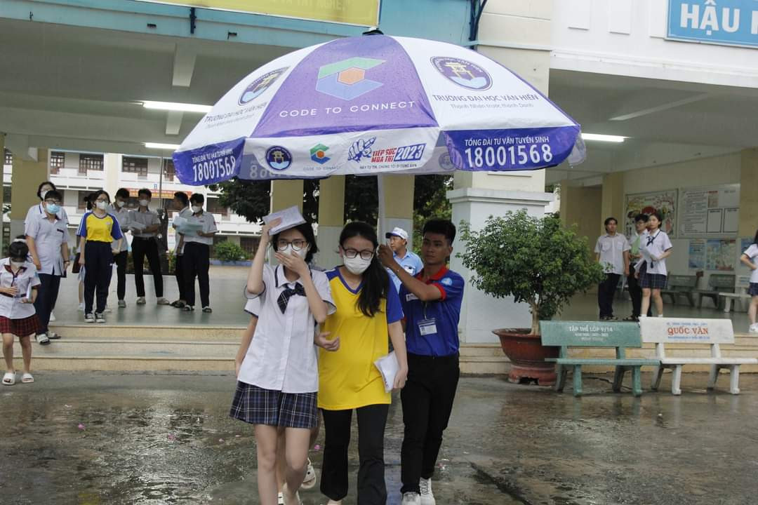 Các tình nguyện viên không ngại trời mưa, che dù cho các thí sinh sau khi kết thúc môn thi. (Ảnh: Hội Sinh viên TP. HCM)