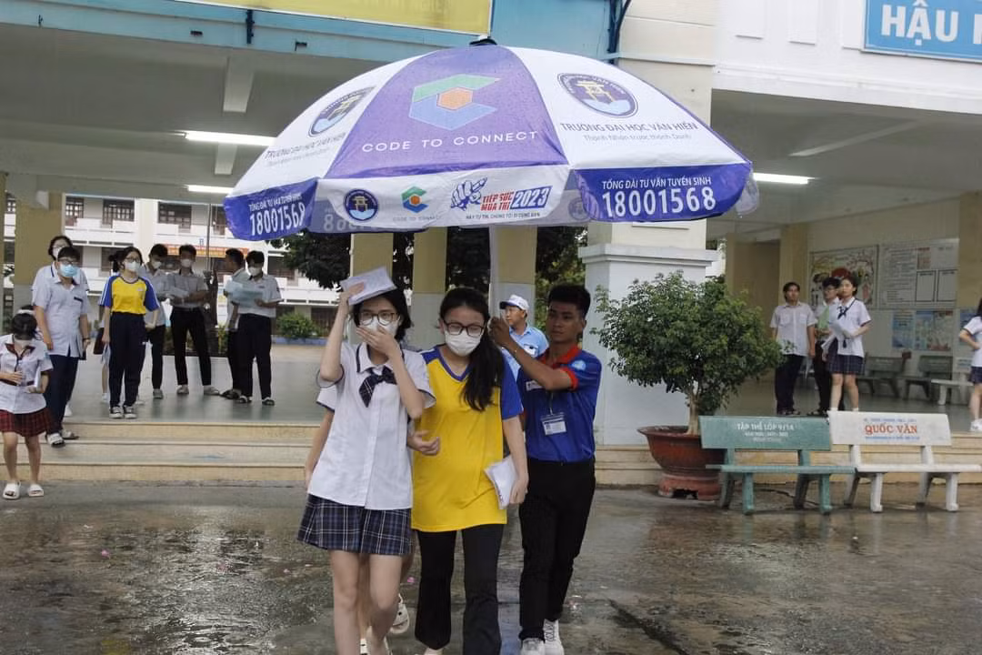 Các tình nguyện viên không ngại trời mưa, che dù cho các thí sinh sau khi kết thúc môn thi. (Ảnh: Hội Sinh viên TP. HCM)