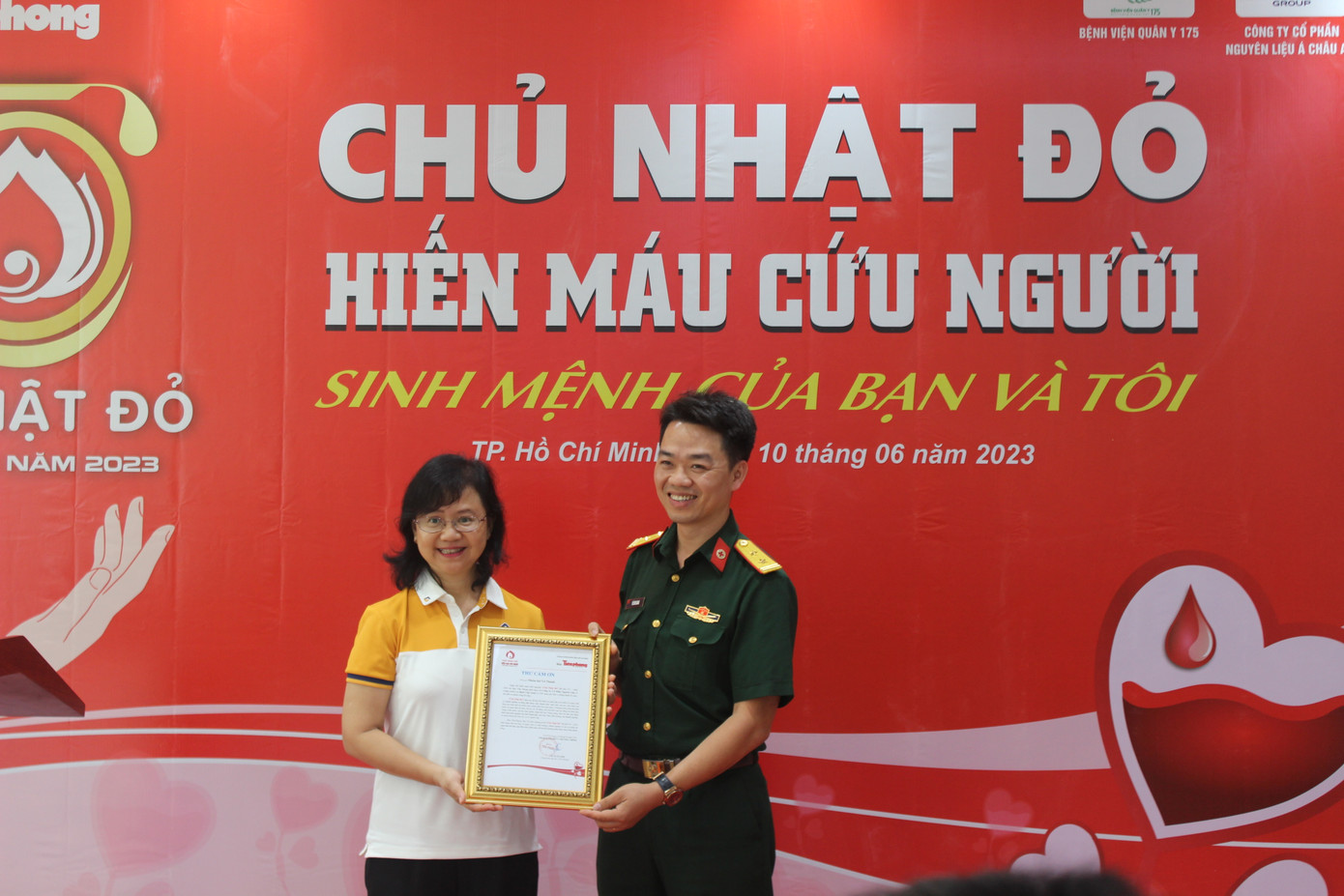 BS Vũ Sơn Giang (bên phải), Phó Chủ nhiệm Chính trị Bệnh viện Quân y 175 trao thư cảm ơn với đơn vị phối hợp tổ chức chương trình là Tập đoàn nguyên liệu Á Châu AIG.