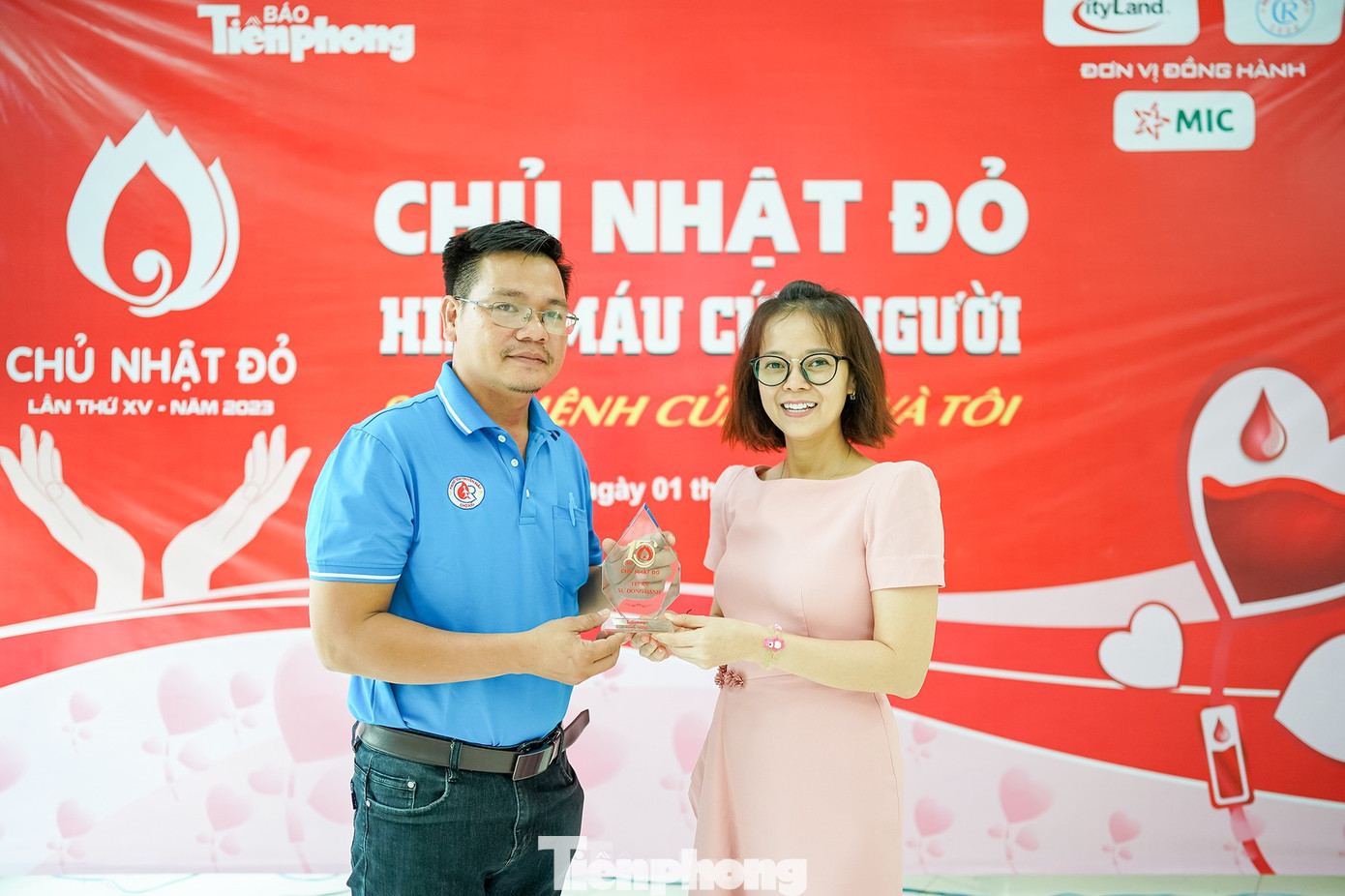 Ông Võ Thành Đông (bến trái), đại diện đội ngũ y tế Bệnh viện Chợ Rẫy nhận kỷ niệm chương từ đại diện Ban Tổ chức ngày hội hiến máu &quot;Chủ nhật Đỏ&quot;. (Ảnh: Phạm Nguyễn)