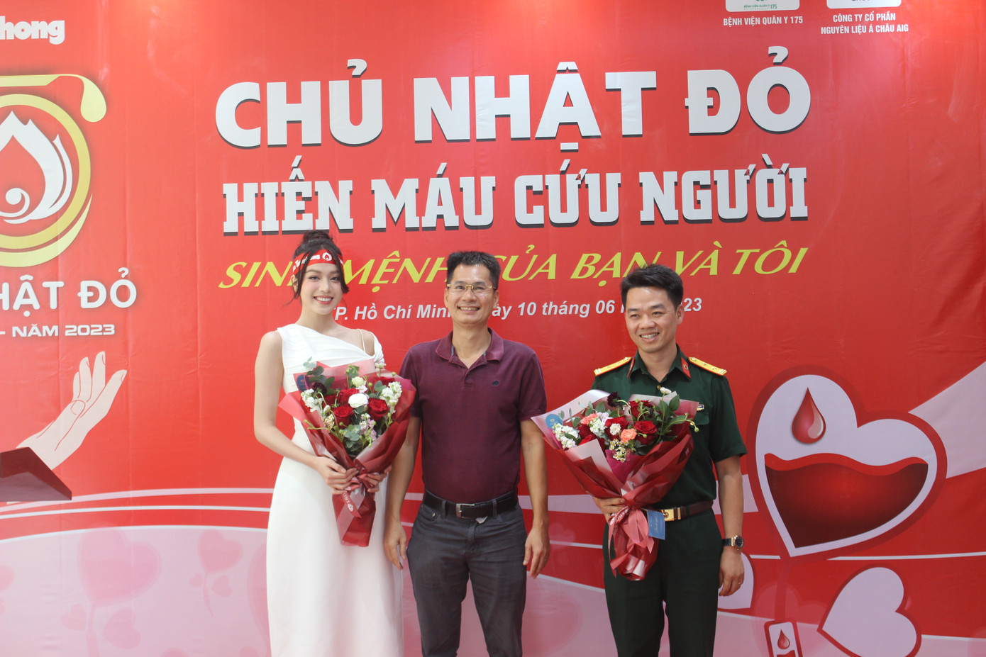 Nhà báo Lý Thành Tâm (giữa) trao hoa cảm ơn với BS - Trung tá Vũ Sơn Giang (phải), Phó Chủ nhiệm Chính trị Bệnh viện Quân y 175 và Hoa hậu Việt Nam 2022 Huỳnh Thị Thanh Thủy (trái).