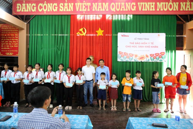 Nhà báo Lý Thành Tâm (áo trắng) cùng Phó Chủ tịch UBND huyện Cẩm Mỹ Lê Văn Tường trao tượng trưng món quà thẻ bảo hiểm y tế cho các em học sinh. (Ảnh: Ngô Tùng)