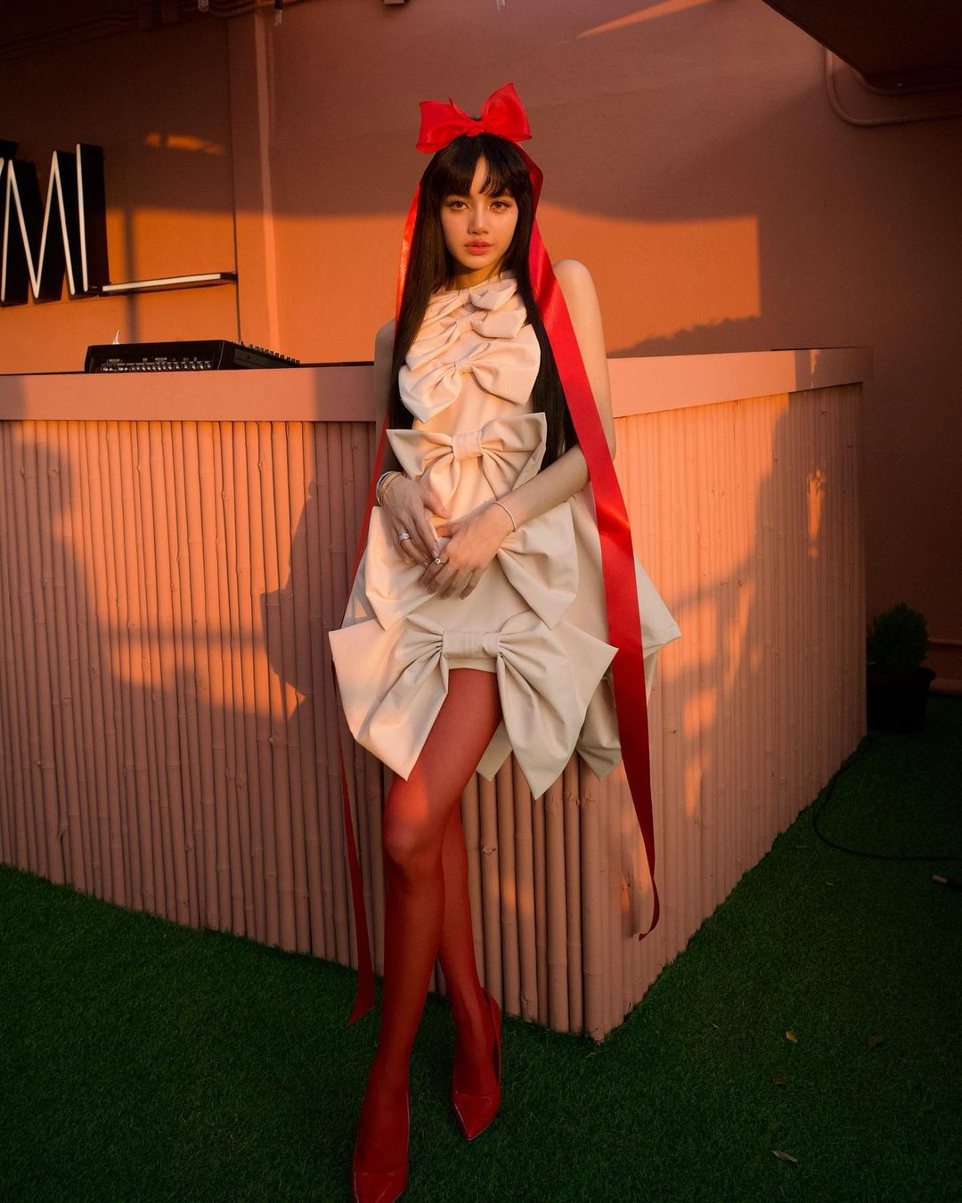 Trong dịp đặc biệt, Lisa xuất hiện với diện mạo vừa dễ thương vừa quyến rũ. Cô mặc chiếc váy ngắn không tay sáng màu, gắn nhiều nơ với các kích thước khác nhau. Điểm nhấn là chiếc nơ đỏ gắn trên đỉnh đầu. Cô phối tất chân và giày cao gót màu đỏ khoe đôi chân dài trứ danh. Ảnh: IG.