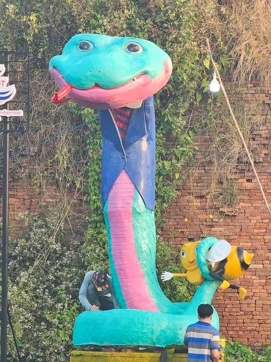 Linh vật rắn màu xanh mặc vest ở Làng Văn hóa Du lịch Chợ Lách (Bến Tre) có ngoại hình độc đáo, gây cười. Đuôi rắn quắp lấy một con ong. Sản phẩm lấy ý tưởng từ bức tranh có tên Xà Rang Hae của anh Trần Thành Đạt, sống tại Bình Định.