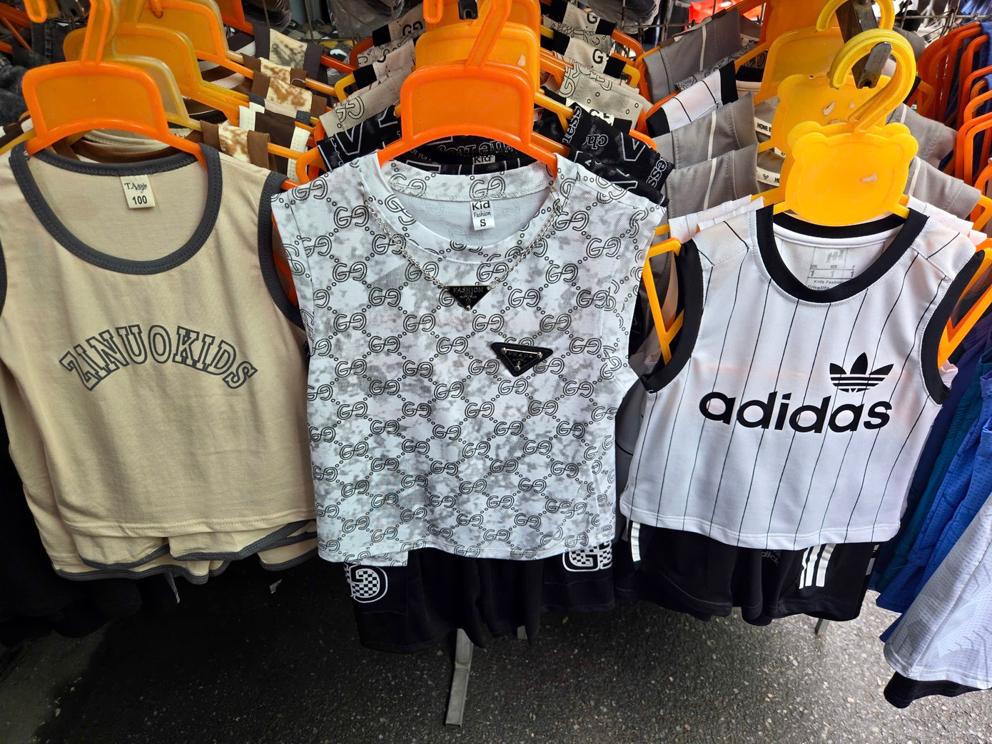 Quần áo trẻ em in tên thương hiệu Adidas, Balenciaga. Chủ cửa hàng cho biết mỗi bộ có giá khoảng hơn 100.000 đồng. Tuy nhiên, khi thấy người mua đắn đo, thái độ của người bán không mấy niềm nở.