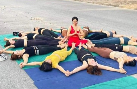 Nhóm phụ nữ trải thảm, tạo dáng giống như tập yoga ở giữa đường để chụp ảnh. Nhóm phụ nữ trải thảm, tạo dáng giống như tập yoga ở giữa đường để chụp ảnh.