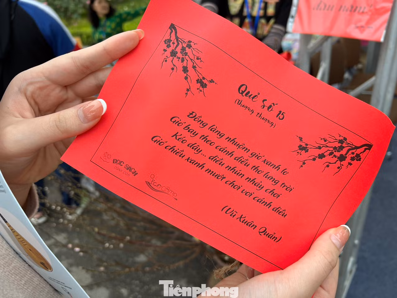 Một độc giả nhỏ tuổi khoe quẻ bói vừa bốc được tại Đường sách. Mỗi quẻ bói tương ứng với bốn câu thơ. Ảnh: NGỌC ÁNH.
