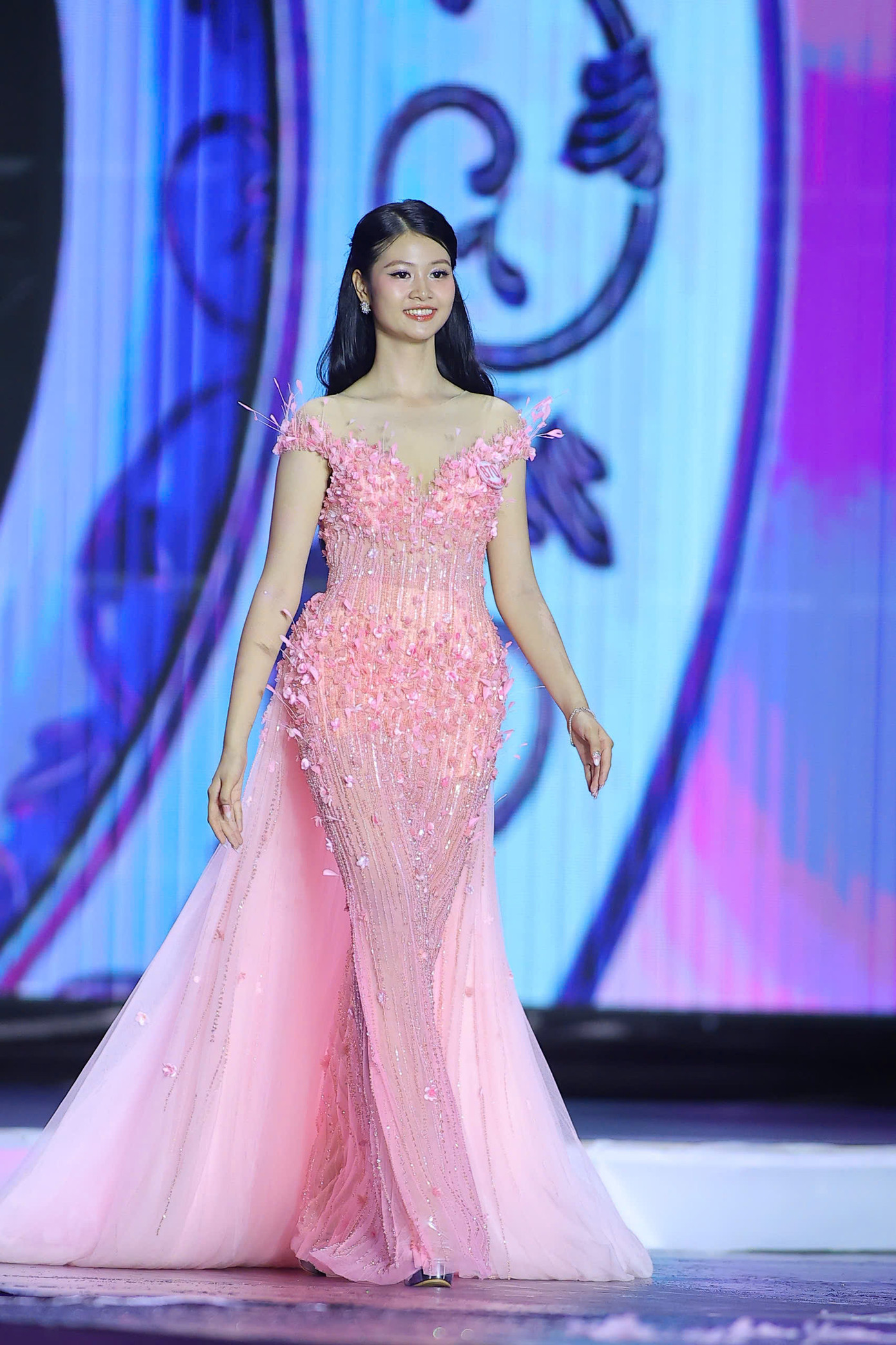 Thí sinh Hồ Ngọc Phương Linh đến từ Hà Tĩnh catwalk với váy dạ hội màu hồng. Phương Linh có gương mặt được khen đẹp như búp bê.