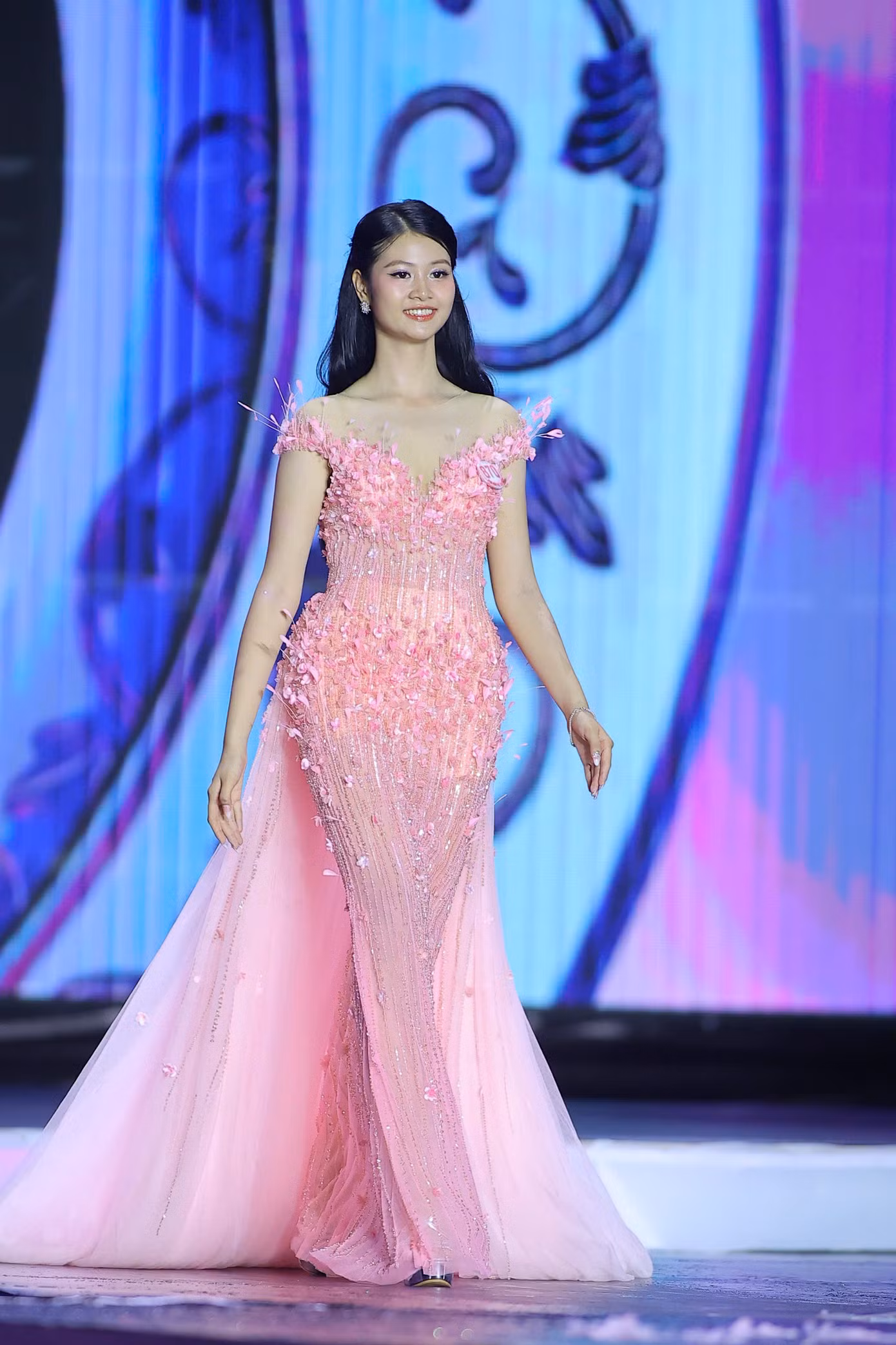 Thí sinh Hồ Ngọc Phương Linh đến từ Hà Tĩnh catwalk với váy dạ hội màu hồng. Phương Linh có gương mặt được khen đẹp như búp bê.