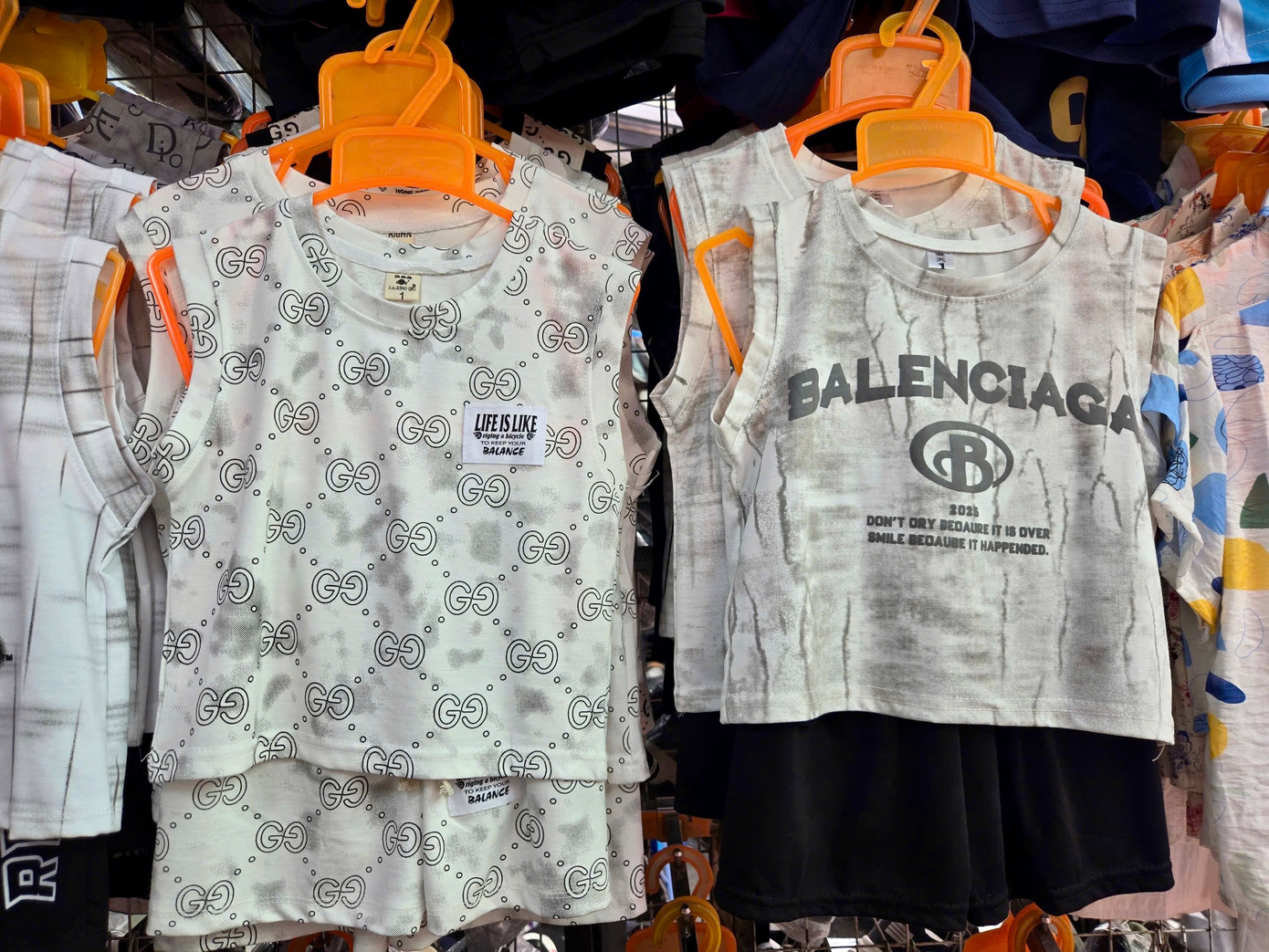 Quần áo trẻ em in tên thương hiệu Adidas, Balenciaga. Chủ cửa hàng cho biết mỗi bộ có giá khoảng hơn 100.000 đồng. Tuy nhiên, khi thấy người mua đắn đo, thái độ của người bán không mấy niềm nở.