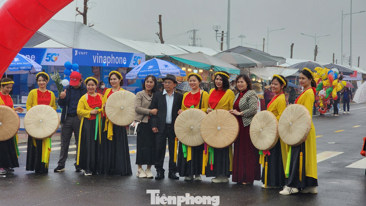 Người dân diện trang phục quan họ mớ ba, mớ bảy chụp ảnh làm kỷ niệm. Hội Lim rực rỡ sắc màu dù thời tiết mưa rét. Du khách có thể quét mã QR quanh khu vực tổ chức để tìm hiểu thông tin về lễ hội. Ảnh: TRỌNG QUÂN.