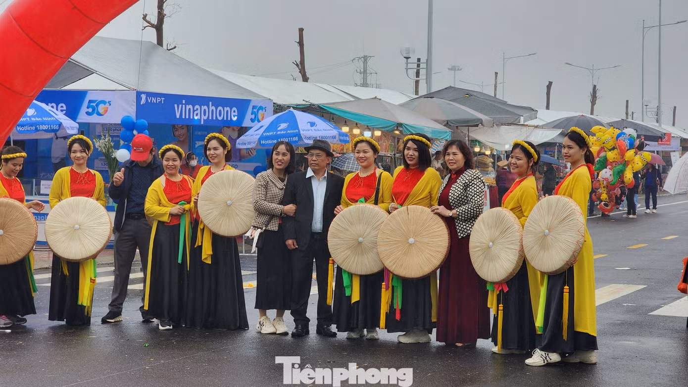 Người dân diện trang phục quan họ mớ ba, mớ bảy chụp ảnh làm kỷ niệm. Hội Lim rực rỡ sắc màu dù thời tiết mưa rét. Du khách có thể quét mã QR quanh khu vực tổ chức để tìm hiểu thông tin về lễ hội. Ảnh: TRỌNG QUÂN.
