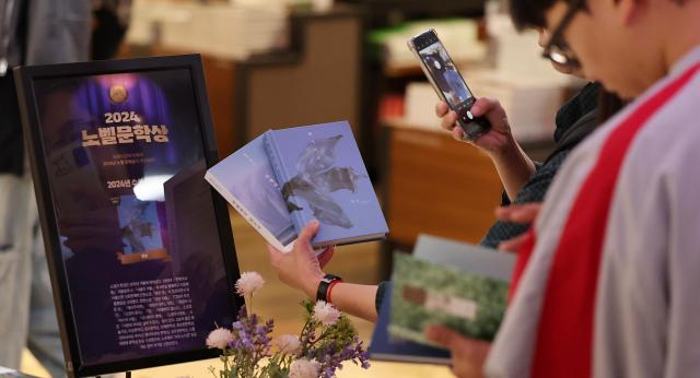 Phóng viên Hàn Quốc ghi lại khoảnh khắc một người dân chụp ảnh những cuốn sách của Han Kang vào chiều 10/10 tại Trung tâm Sách Kyobo ở Seoul. Ảnh: MK. Phóng viên Hàn Quốc ghi lại khoảnh khắc một người dân chụp ảnh những cuốn sách của Han Kang vào chiều 10/10 tại Trung tâm Sách Kyobo ở Seoul. Ảnh: MK.