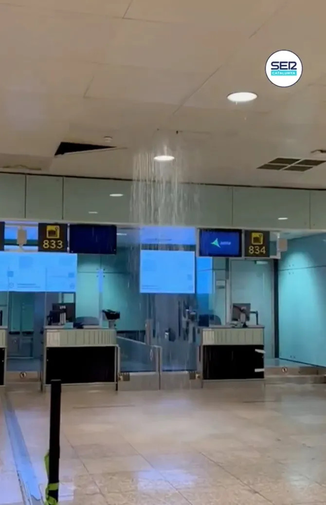 Hành khách bì bõm lội nước qua sảnh khởi hành ở sân bay El Prat. Ảnh: X.