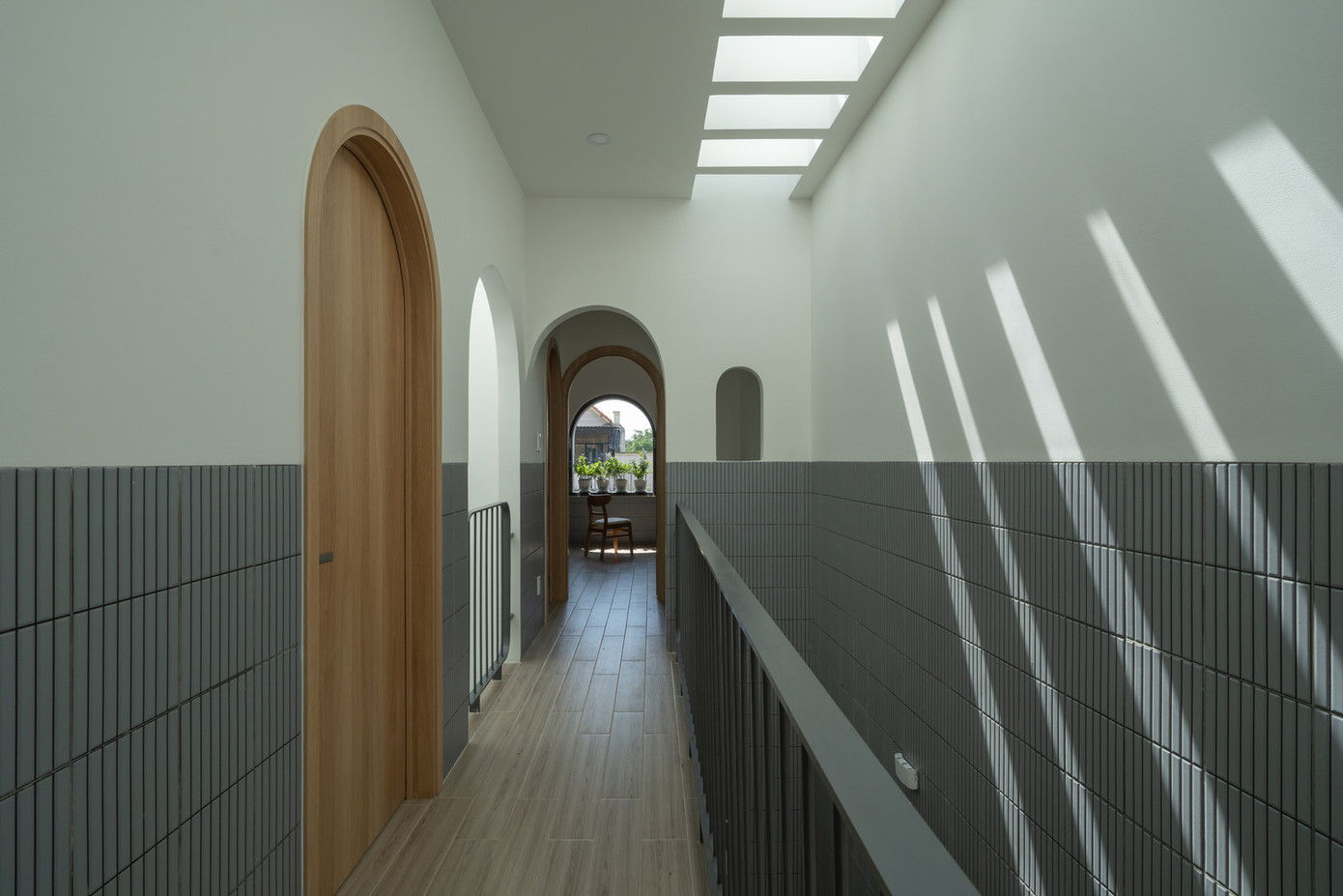 Tầng trên có ba phòng ngủ và một phòng tắm chung. Một giếng trời ở giữa, kết hợp với cây xanh, nối liền hai tầng.