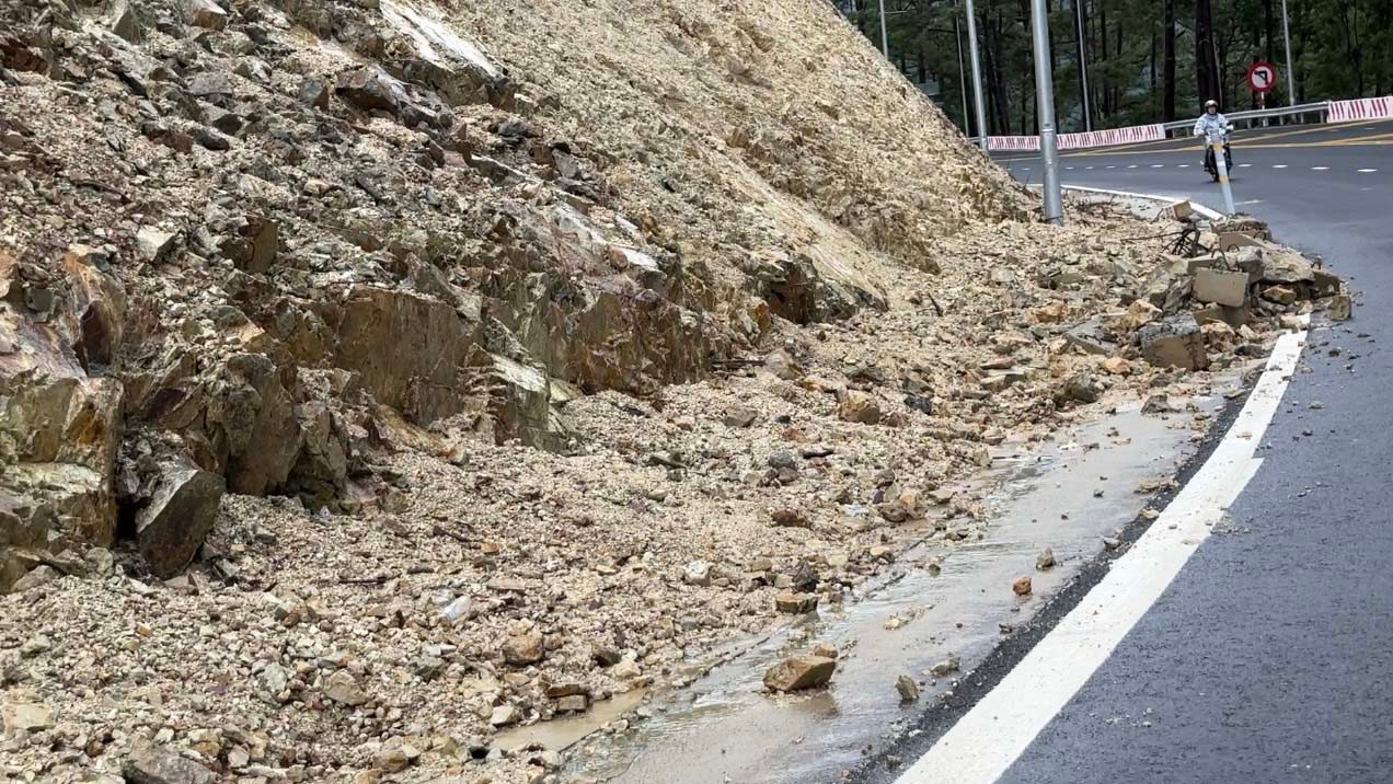 Một vị trí sạt lở ở taluy dương khiến đất đá đổ xuống lấp mương, nước tràn lên mặt đường.