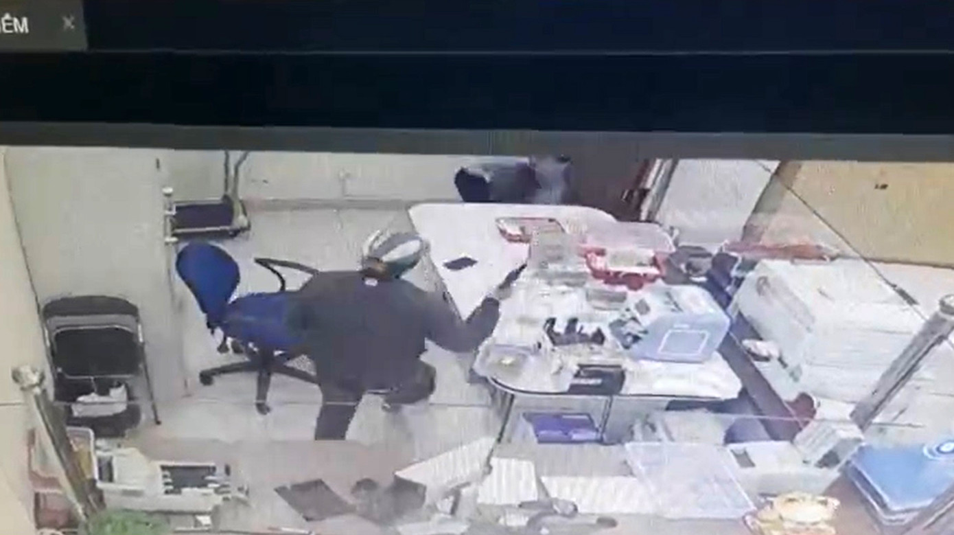 Tên cướp tay lăm lăm khẩu súng, vào bên trong quầy giao dịch để cướp tiền