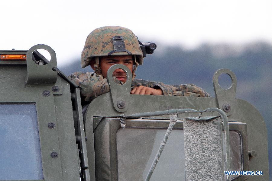 Một binh lính Mỹ đứng nhìn về phía các phương tiện chiến đấu đang diễn tập 