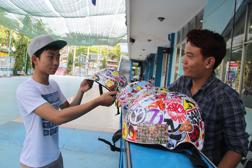 Kiều Vũ Minh Thông dán sticker lên mũ và giao cho khách. Một lần dán, khoảng 80.000 đồng với 50 miếng sticker cho một chiếc mũ.