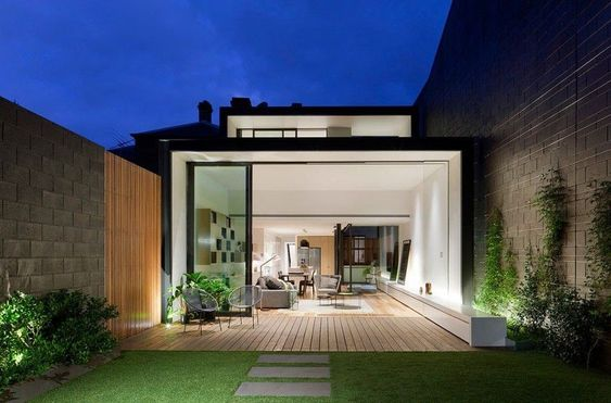 Với mẫu nhà ống 1 tầng này, hệ thống cửa được thiết kế rộng, thông thoáng giữa nội thất và ngoại thất, tận dụng đón gió từ bên ngoài cũng như ánh sáng tự nhiên, giúp ngôi nhà tiếp xúc với thiên nhiên. Phía ngoài có hiên được lát gỗ, đủ rộng để có thể kê 1 bộ bàn ghế làm nơi thư giãn, tắm nắng vào buổi sớm và thưởng trà vào buổi chiều, đêm. Điện được lắp đặt tinh tế, bên ngoài khu vực dưới tán cây, tạo hiệu ứng sáng hắt lên, làm cho ngôi nhà thêm hiện đại, sang trọng hơn.