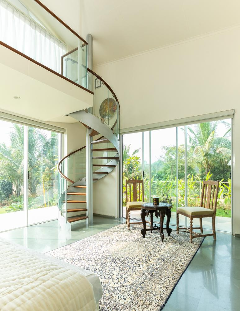 Để không gian trong nhà luôn ngập ánh sáng tự nhiên, hệ thống cửa thay vì dùng gỗ được thay thế bằng kính trong suốt. Thay vì làm gác lửng kéo dài toàn bộ ngôi nhà, các kiến trúc sư chỉ làm một gác lửng nhỏ ở phòng khách, mọi người có thể leo cầu thang dạng xoắn lên xuống gác lửng này để quan sát mọi thứ trong nhà.