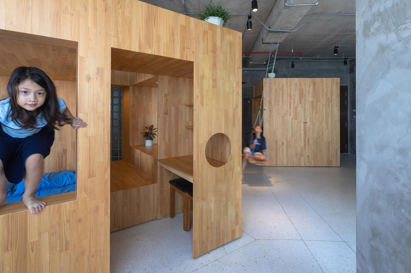 Trung tâm căn hộ đặt một hộp gỗ có kích thước 3x3m, cao 2,2m, gồm các chức năng: Giường ngủ 2 tầng, nơi làm việc, nơi học tập, tủ kệ…