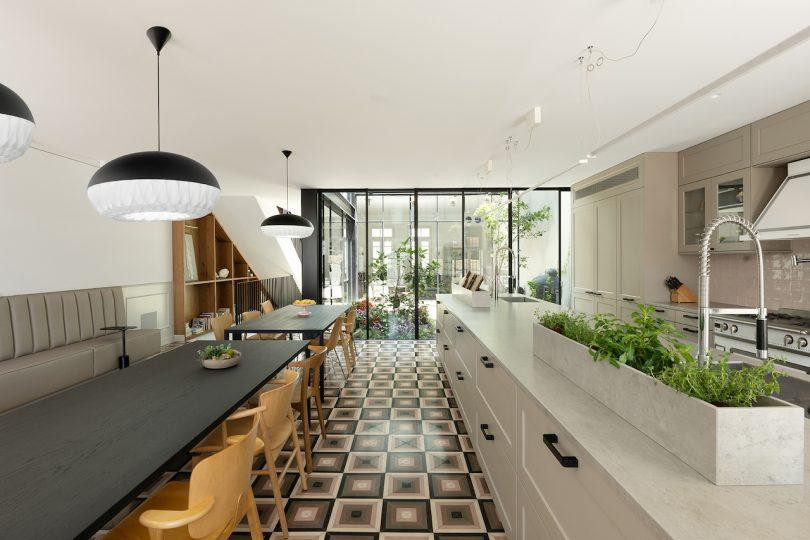 Tại tầng 1, đảo bếp kéo dài theo diện tích của khu vực ăn uống và bàn đọc sách, tiếp giáp với khu vườn ở sân trong.