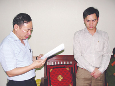 Trọng (phải) đứng nghe tống đạt lệnh bắt giam