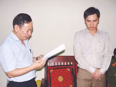 Trọng (phải) đứng nghe tống đạt lệnh bắt giam
