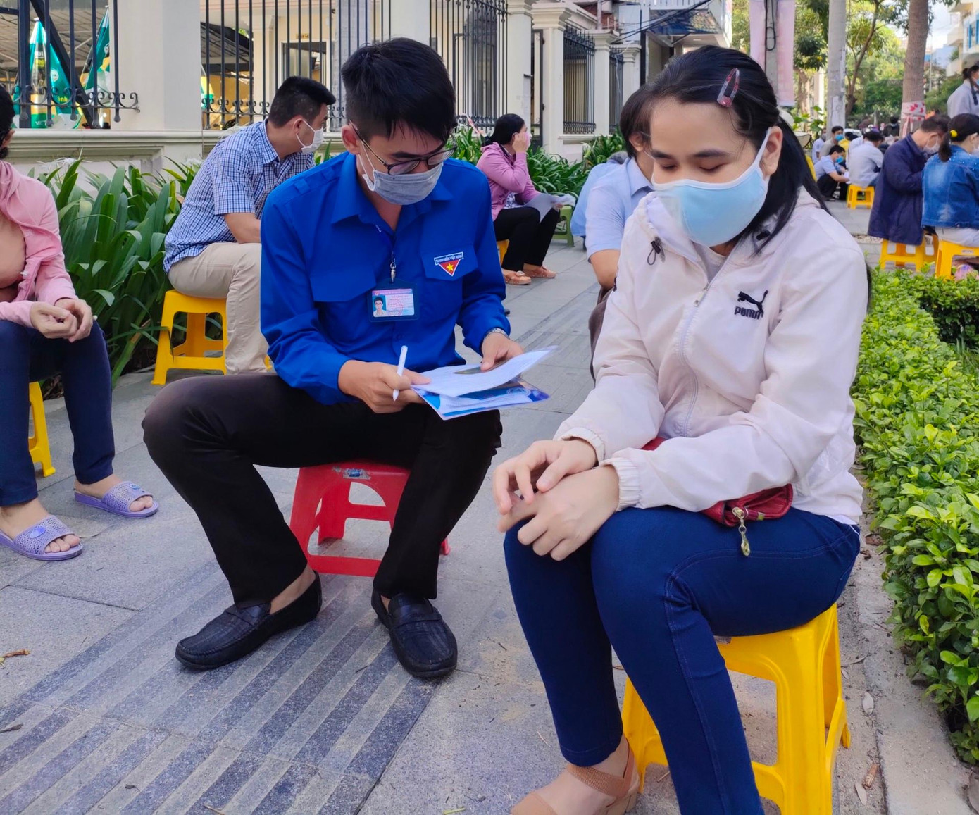 Lực lượng thanh niên lấy thông tin điền vào tờ khai tiêm vắc-xin cho người khiếm thị. Ảnh L.H Lực lượng thanh niên lấy thông tin điền vào tờ khai tiêm vắc-xin cho người khiếm thị. Ảnh L.H