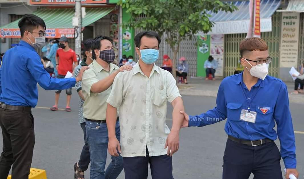 Lực lượng thanh niên đưa người khiếm thị qua đường để tiêm vắc-xin. Ảnh VĨNH THÀNH Lực lượng thanh niên đưa người khiếm thị qua đường để tiêm vắc-xin. Ảnh VĨNH THÀNH