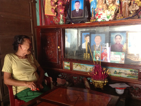 Bà Quế xót xa nhìn một loạt di ảnh của người thân trong chiếc tủ kính. Bà Quế xót xa nhìn một loạt di ảnh của người thân trong chiếc tủ kính