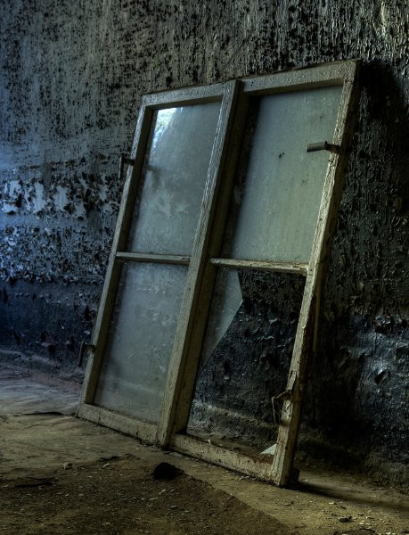 Một cánh cửa sổ vỡ âm thầm tựa vào tường