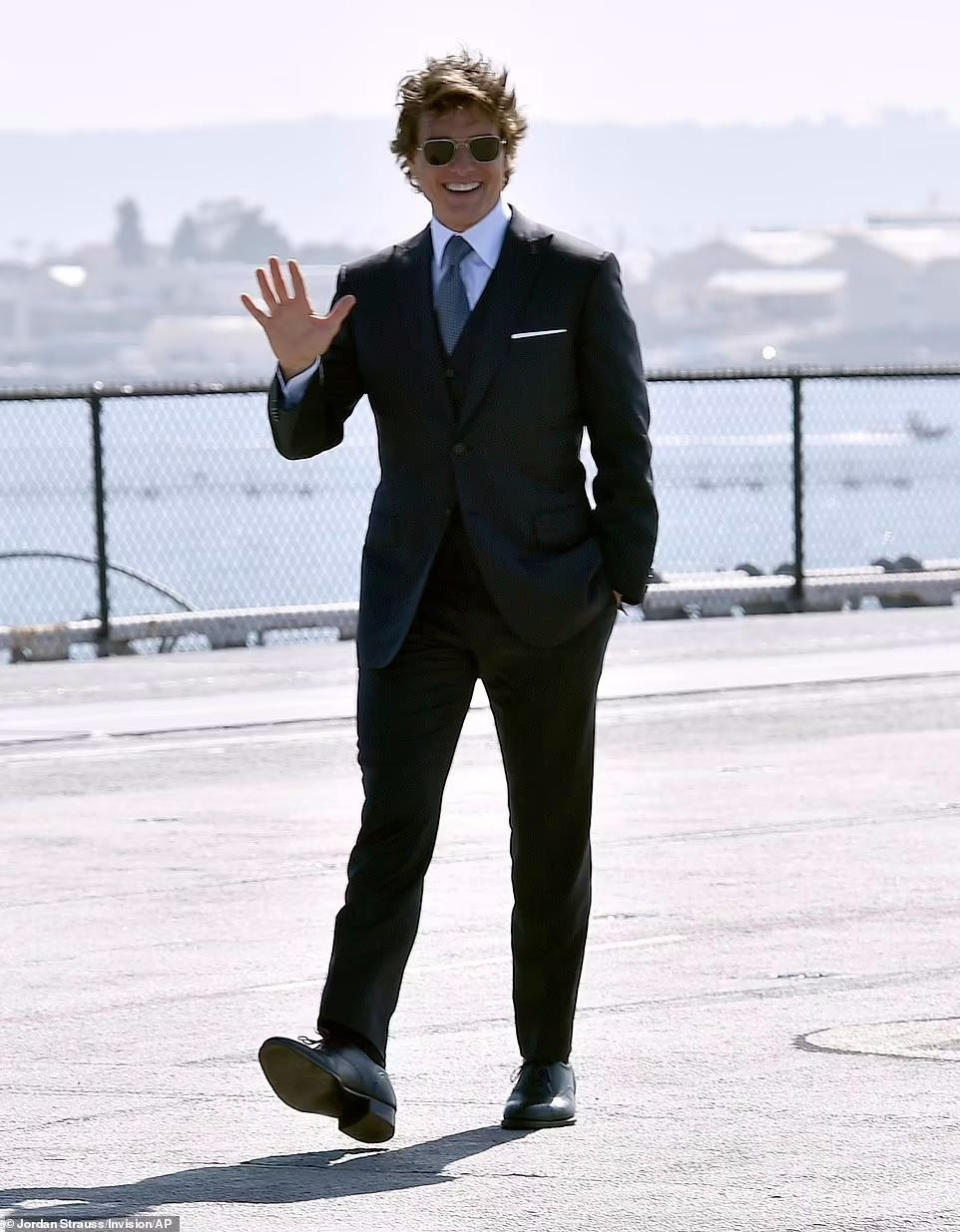 Bước xuống trực thăng, Tom cười rạng rỡ tiến vào khu vực thảm đỏ. Ngôi sao "Nhiệm vụ bất khả thi" mặc Âu phục màu đen, kết hợp sơ mi trắng, cà vạt xám và giày da đen cùng mắt kính râm.