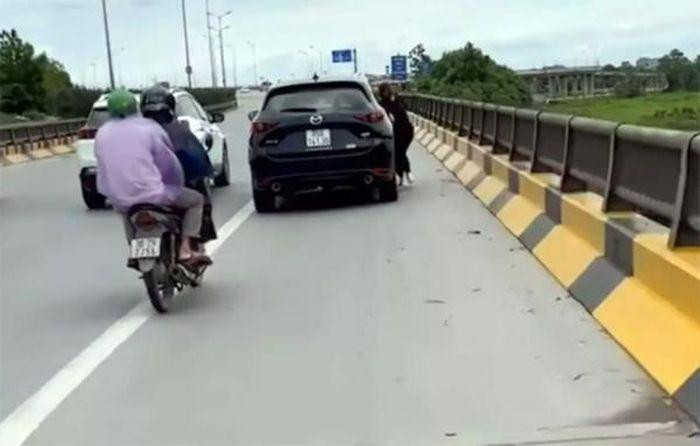 Người phụ nữ đu bám vào ô tô đang chạy. Ảnh cắt từ clip Người phụ nữ đu bám vào ô tô đang chạy. Ảnh cắt từ clip