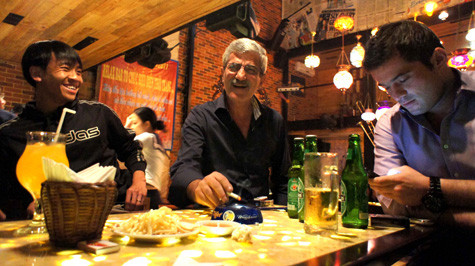 Trung vệ Minh Đức và HLV Calisto cười đùa vui vẻ tại bar, trong khi cậu con trai Tiago của ông thầy người Bồ còn mải mê với chiếc điện thoại.