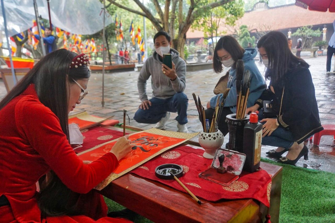 Từng nét thư pháp hiện ra trên đôi bàn tay tài hoa của "cô đồ" Nhung uốn lượn như phượng múa, rồng bay. Nhiều người xếp hàng chờ đến lượt cho chữ. Là một khách quen, 3 năm nay, năm nào chị Lê Hồng Thắm (Yên Dũng, Bắc Giang) cũng xin chữ "cô đồ". Chị Thắm cho biết, ở chùa Vĩnh Nghiêm có 3 -4 "thầy đồ" cho chữ, nhưng chị chỉ thích và xin chữ "cô đồ" Nhung.