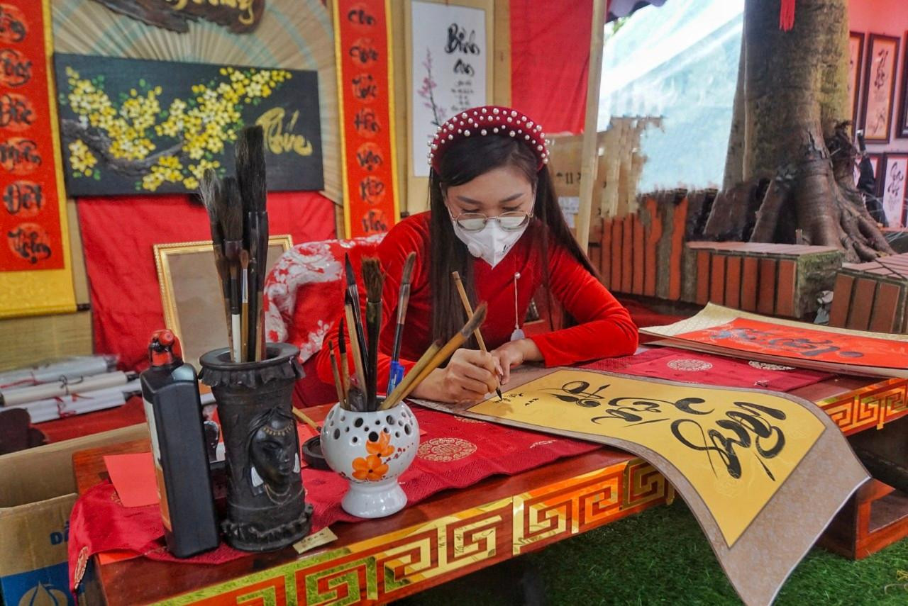 "Cô đồ" là Nguyễn Thị Cẩm Nhung, Sinh viên ngành mỹ thuật, Học viện Hồng Hà (Vân Nam, Trung Quốc). Khác hẳn với hình ảnh ông đồ già, râu tóc bạc phơ ngồi viết chữ, nhiều năm nay, người đi lễ chùa Vĩnh Nghiêm dịp đầu Xuân đã quen thuộc với hình ảnh "cô đồ" Cẩm Nhung (Tân Yên, Bắc Giang) mặc áo dài, đội vấn đỏ say sưa với những dòng thư pháp. Xuân này, "đồ Nhung" đã có 7 năm viết thư pháp tại chùa Vĩnh Nghiêm.